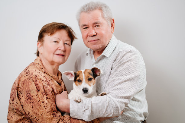 白色背景下，一对年迈的夫妇带着一只狗。图片下载