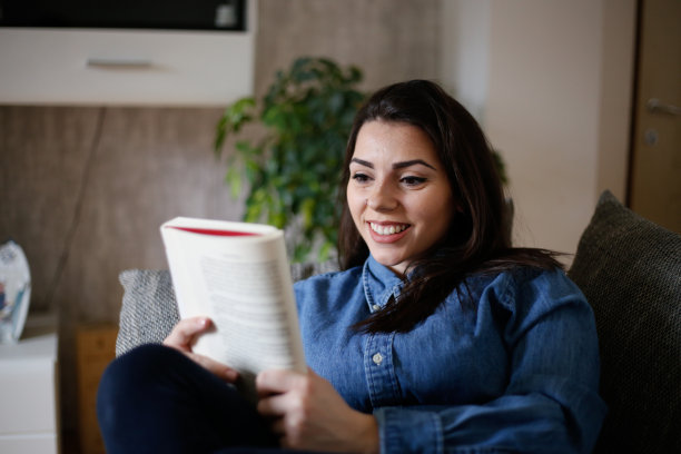 一个女人在隔离期间在家看书。库存图片图片下载