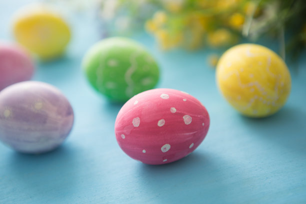 蓝色的木桌上用花朵装饰着复活节彩蛋图片下载