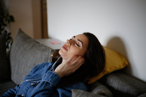 年轻女子在床上听音乐的照片图片下载