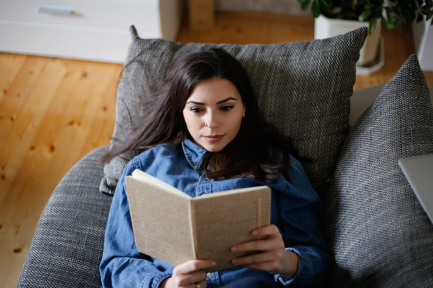 一个女人在隔离期间在家看书。库存图片图片下载