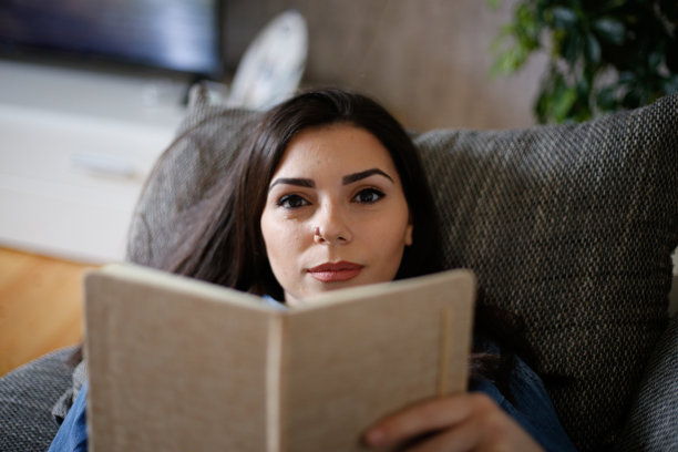 一个女人在隔离期间在家看书。库存图片图片下载