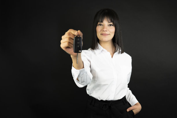 有车钥匙的女人。孤立在黑色背景上。图片下载
