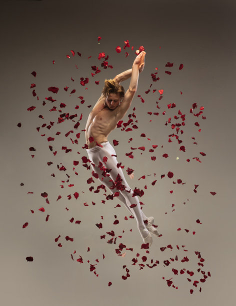 年轻优雅的芭蕾舞演员在玫瑰花瓣的背景下。艺术，运动，动作，灵活性，灵感概念。图片下载