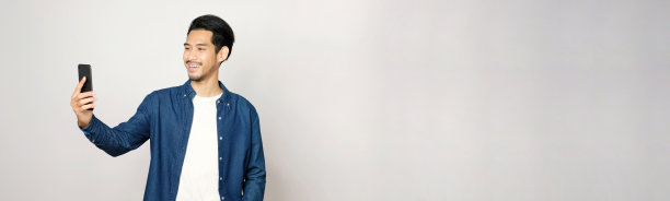 视频电话会议，快乐的亚洲人有一个视频聊天手机，而站在灰色背景与拷贝空间，亚洲男性在智能手机上谈论视频通话，人们使用在线电信，社交距离图片下载