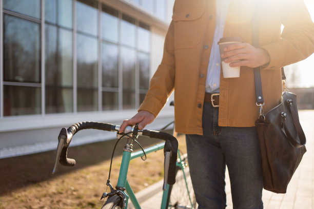 一个不认识的人与他的自行车拿着一杯咖啡走的特写图片下载