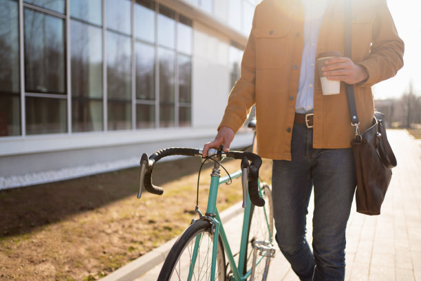 一个不认识的人拿着一杯咖啡骑着自行车走着图片下载