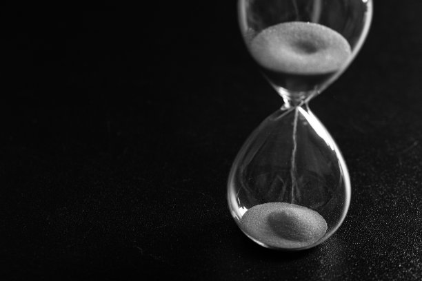 沙子通过一个沙漏测量旅行时间倒计时到最后期限，黑白照片图片下载