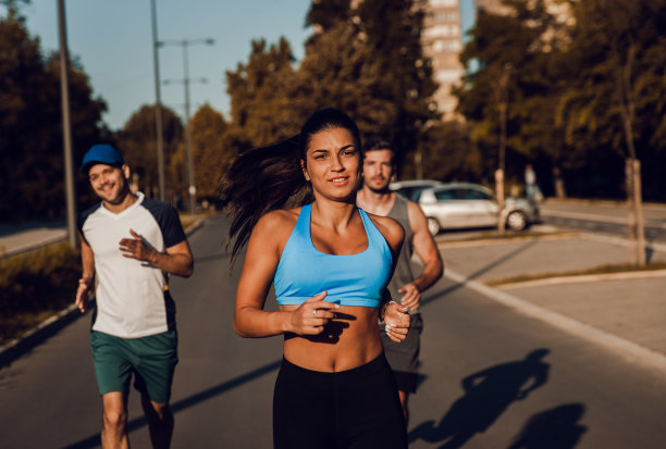 一群年轻的朋友穿着运动服在城市街道上跑步。图片下载