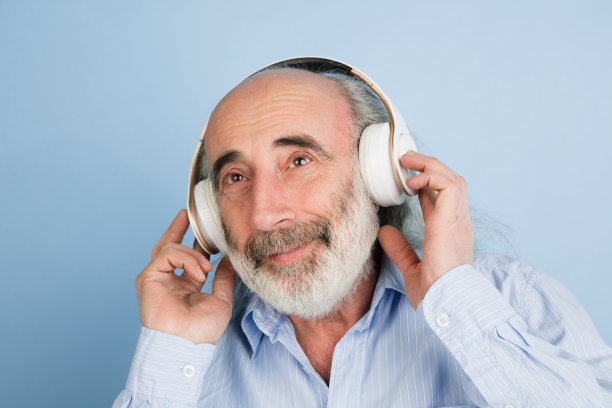 近距离的灰白头发的男子在耳机孤立的光背景。图片下载