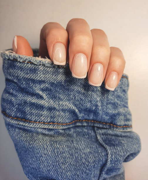 温柔的迷彩指甲油在方形指甲与法国设计。手与专业美甲在牛仔夹克。新潮的法国设计指甲油涂层。图片下载