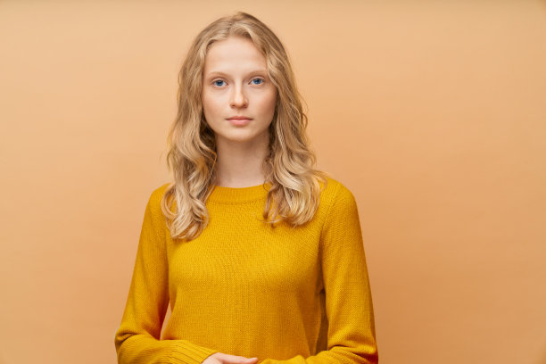 腰部以上的美丽年轻认真聪明的金发北欧女人肖像在明亮的黄色橙色墙壁图片下载