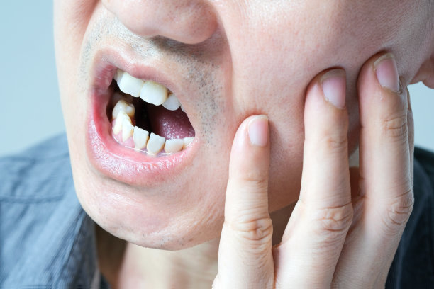 年轻人牙痛得用脸颊碰了碰自己的脸。露出不高兴的表情。健康的概念图片下载