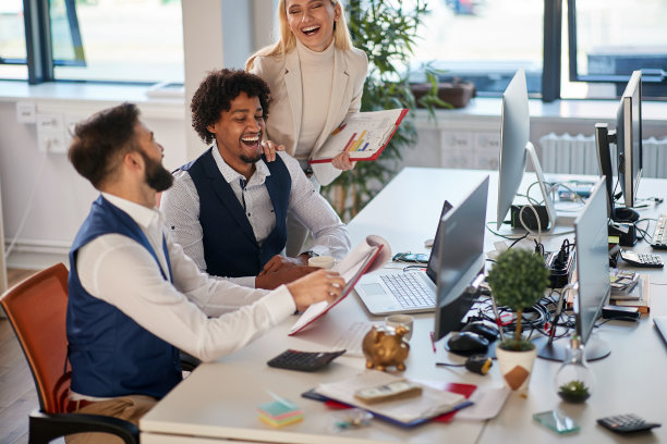 一个同事在办公室里给另一个金发女同事看文件，她在笑。年轻人，现代办公商务图片下载