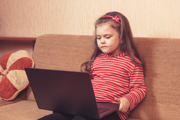 微笑的小女孩使用笔记本电脑进行远程学习或娱乐图片下载