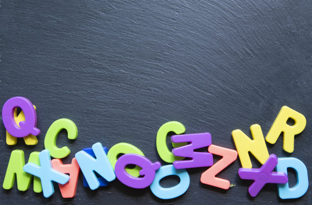 以黑色石头为背景的彩色字母框架。赢富数据。Copyspace。概念回到学校。图片下载