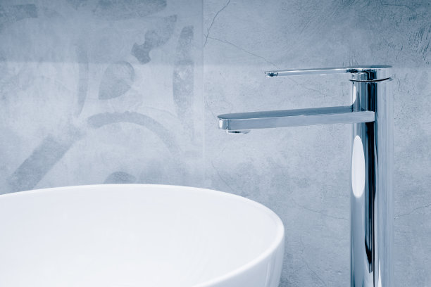 在一个漂亮的灰色浴室里，豪华的水龙头和白色的毛巾放在白色的水槽上。卫生防病毒理念。图片下载