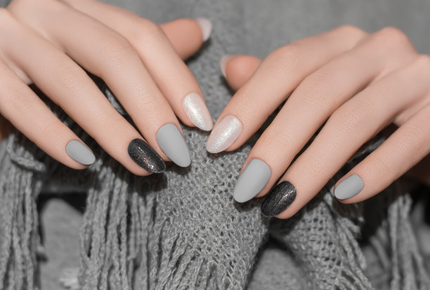 女性的手与闪光的银色指甲设计。银色指甲油修指甲。女人手里拿着灰色羊毛披肩图片下载