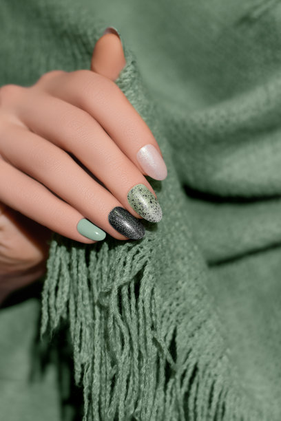 女性手与亮绿色指甲设计。黑色指甲油美甲。女人手里拿着绿色羊毛披肩图片下载