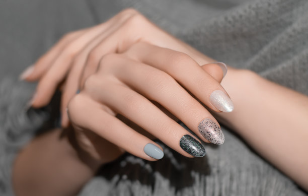 女性的手与闪光的银色指甲设计。银色指甲油修指甲。女人手里拿着灰色羊毛披肩图片下载