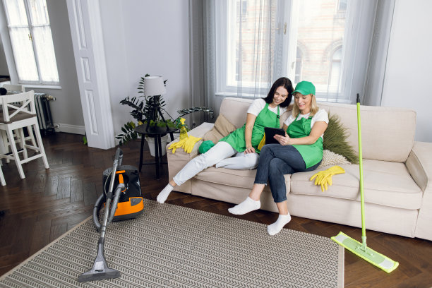 两名女清洁工正在沙发上休息，用着平板电脑图片下载