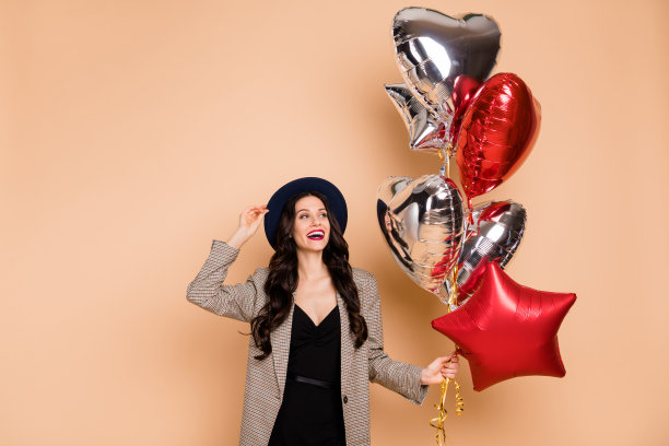 照片肖像的女人戴着帽子保持气球在生日笑孤立在柔和的米色背景图片下载