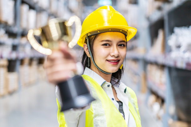 快乐的女仓库工人在被选为优秀员工后拿着奖杯素材图片