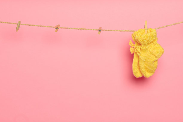 婴儿衣服在晾衣绳上粉红色的背景-图像图片下载