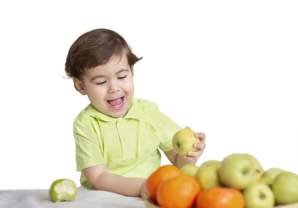 一个快乐的小男孩从果盘里拿苹果的肖像图片下载
