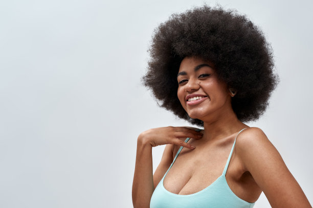 肖像可爱性感的年轻女模特与非洲式发型穿着蓝色内衣微笑在相机，摆出孤立的灯光背景图片下载