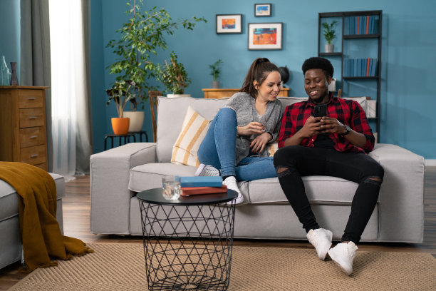 快乐快乐的年轻夫妇坐在沙发上，在现代的房间浏览互联网网站，购买购买，购物，家庭时间，电子商务的概念图片下载