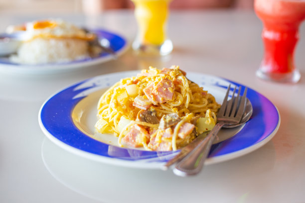 在一家咖啡馆的午餐，卡博纳拉意面装在盘子里，旁边有一杯奶昔图片下载