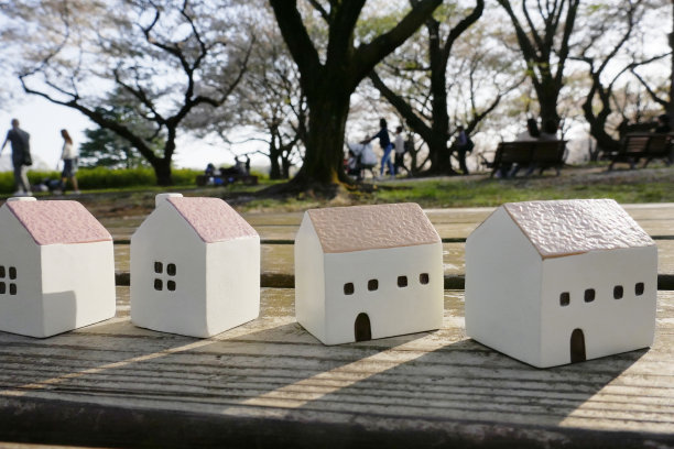 小房子放在木桌上，人们在公园里散步。图片下载