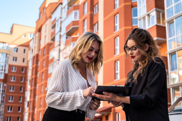 女房地产经纪人与剪贴板钥匙和年轻的女性客户附近的房子出售图片下载
