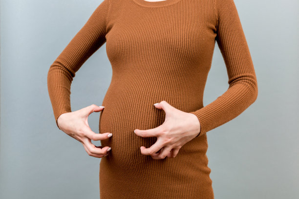 孕妇在彩色背景上抓挠自己的腹部图片下载