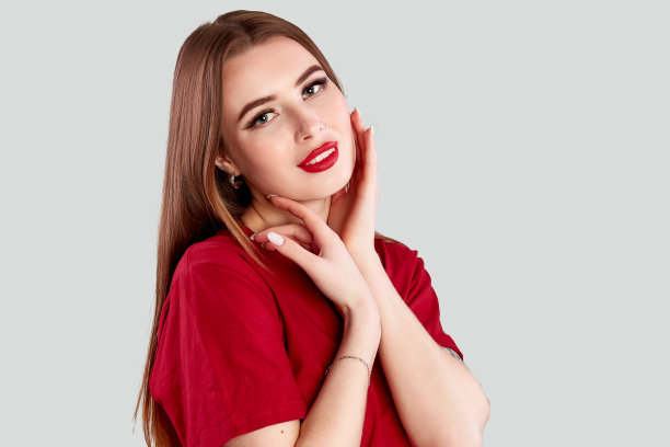 美丽的年轻成年妇女的脸与鼻子耳环和干净新鲜的皮肤。肖像可爱的黑发与红唇和鼻子穿孔摆姿势在红色t恤灰色图片下载