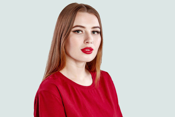 漂亮的脸年轻的成年女性鼻子耳环和干净的新鲜皮肤。可爱的深色皮肤，红唇，穿鼻环，身穿红色t恤，灰色图片下载