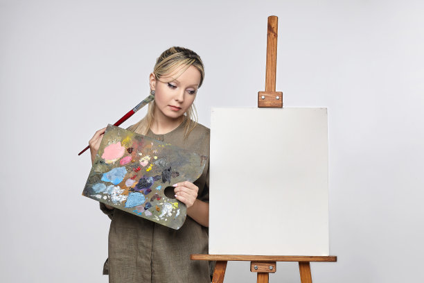 年轻的女艺术家站在一张空白的画布前，思考着要画什么图片下载
