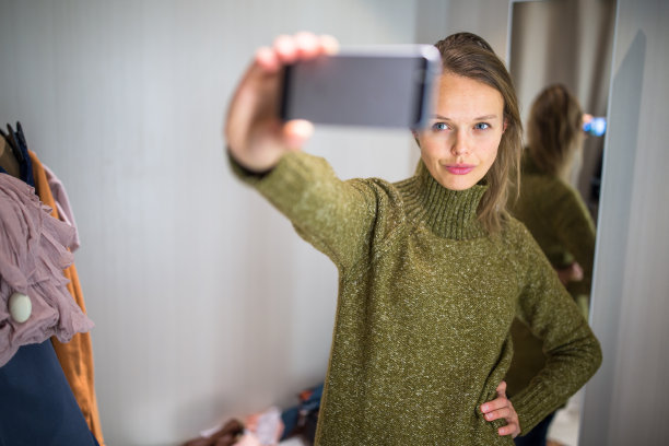 一名年轻女子在一家时装店购物，正在试穿一些衣服图片下载