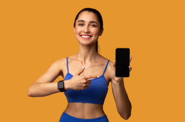 快乐的运动型女人展示带黑色空白屏幕的手机图片下载