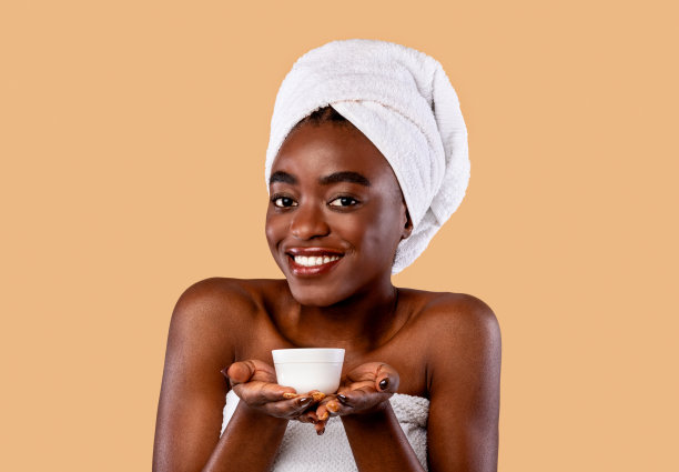 年轻漂亮的非洲裔美国女人，手里拿着一瓶奶油图片下载