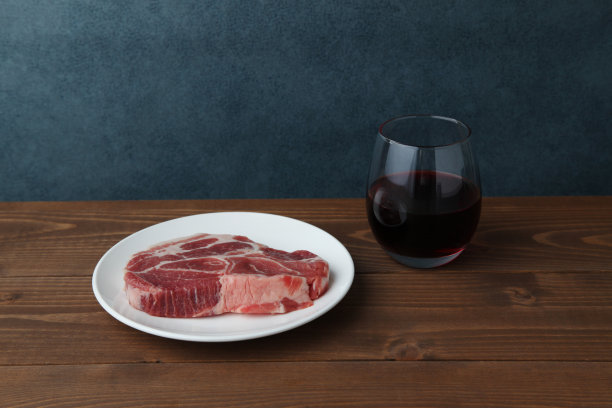 生猪肉和一杯红酒单独放在木桌上图片下载