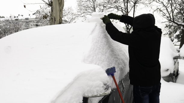 一场暴风雪后的早晨，一个男人在清理一辆被雪覆盖的汽车。图片下载