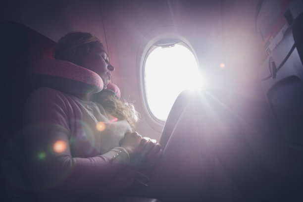 一位女乘客在飞机上用颈垫睡觉。图片下载