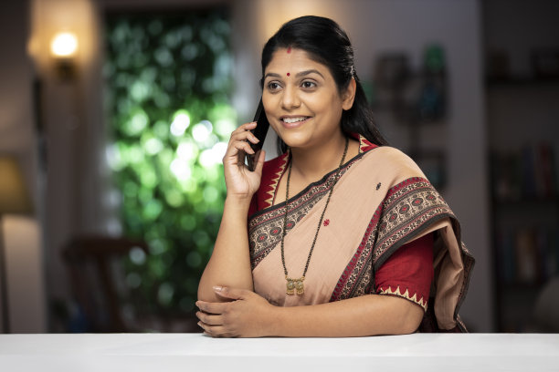 一个中年妇女站在窗户和阳台附近打电话的照片:库存照片图片下载