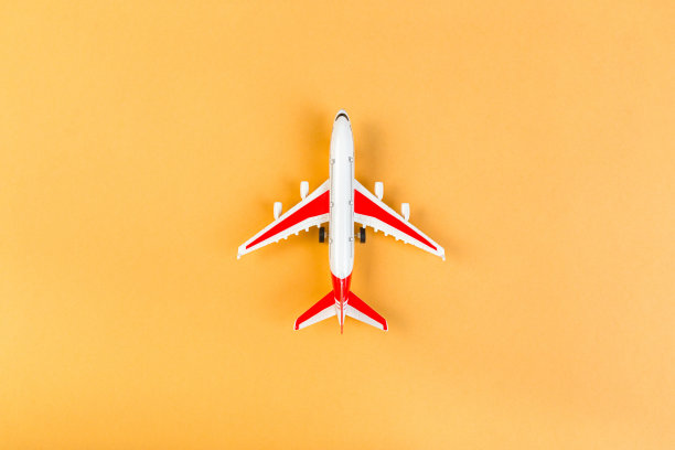 红色机翼的现代飞机的玩具模型。旅游和旅游概念。橙色背景图片下载