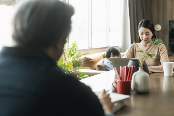 新的正常工作远程在家的概念，亚洲爸爸妈妈在家里工作与笔记本电脑智能手机在餐厅，而他的儿子正在周围玩耍，要求一起玩图片下载