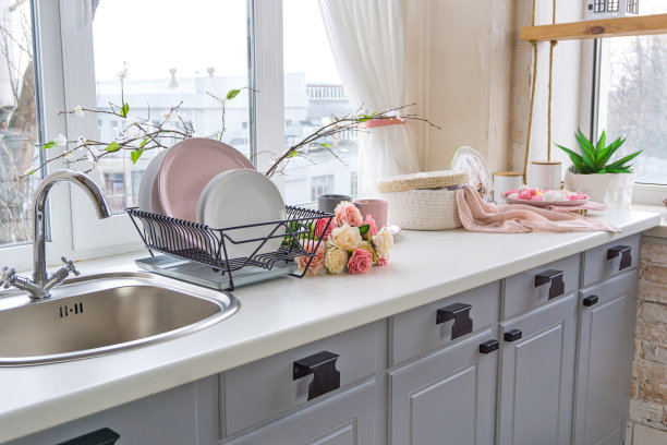 厨房水槽的侧视图，靠近窗户的花和盘子图片下载