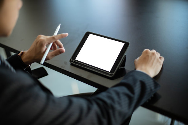 一个年轻的亚洲商人在他的办公室工作。使用黑屏的手机和平板电脑图片下载