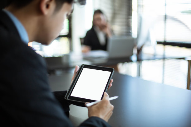 一个年轻的亚洲商人在他的办公室工作。使用黑屏的手机和平板电脑图片下载